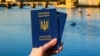 Generic – Woman's hand holding two Ukrainian passports in front of Prague old town cityscape